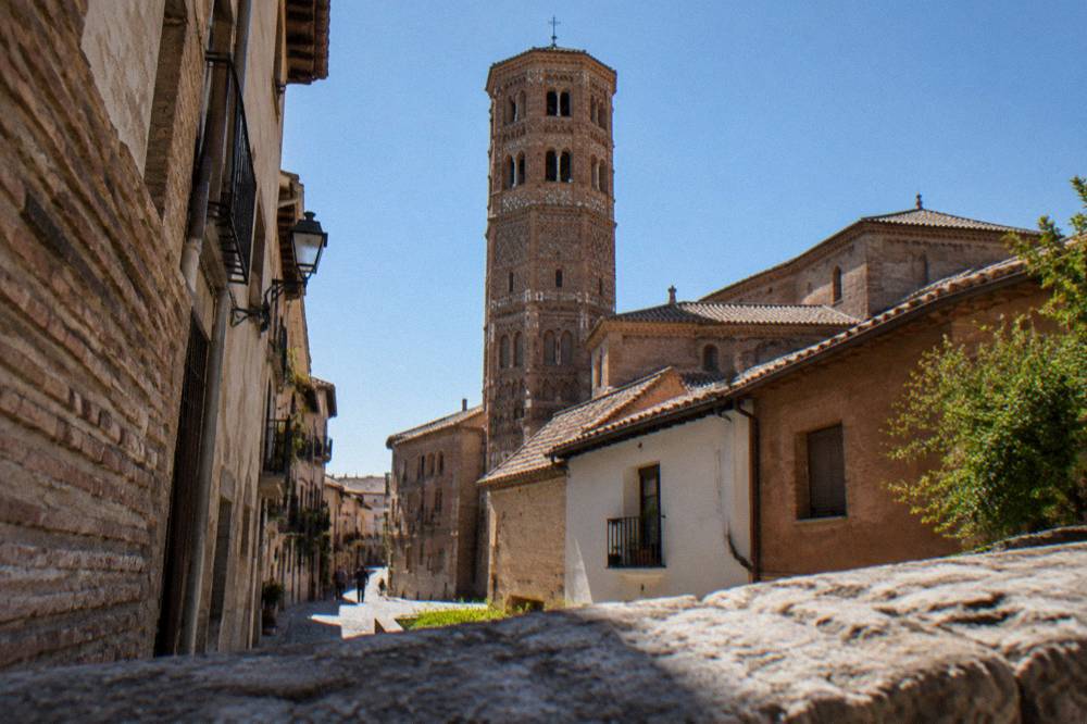 Narrow residential streets with small shops leading toward a brick church tower