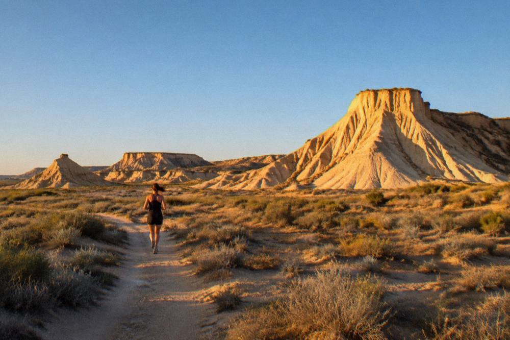 Sunset light turning eroded white clay formations golden across an open badland plain