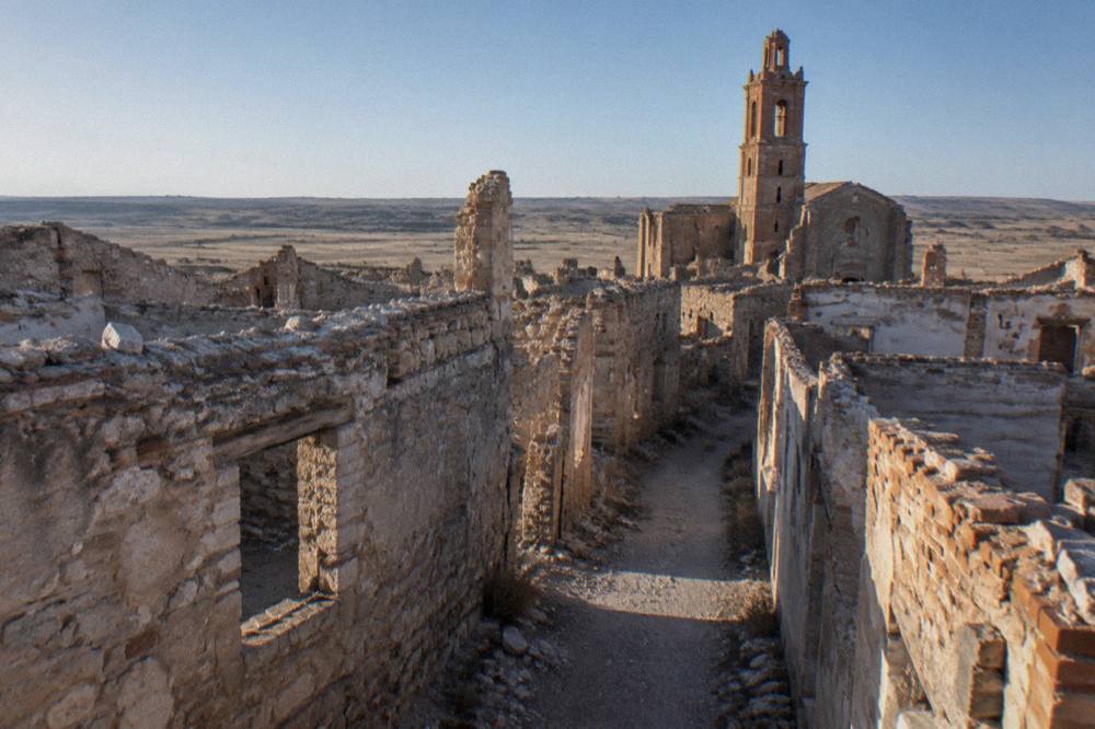 A narrow lane between roofless stone houses in the ruined old town of Belchite