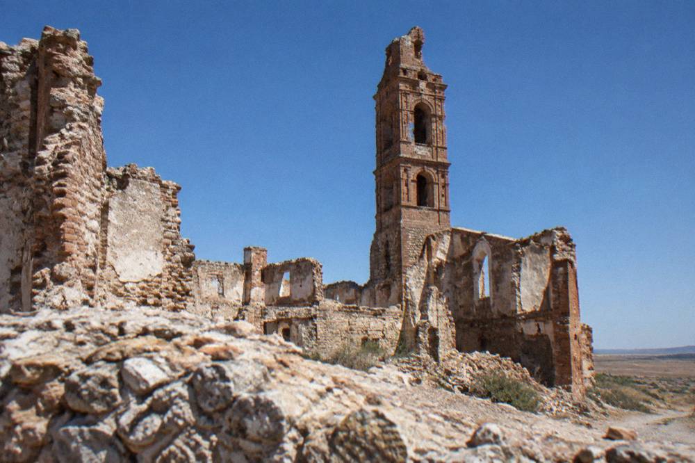 The broken tower of the church of San Martín rising above collapsed stone walls at Belchite