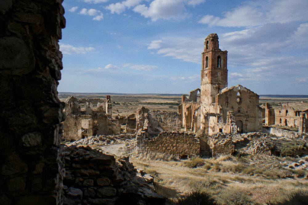 Wide dry plain and low scrub stretching to the horizon beyond the Belchite ruins