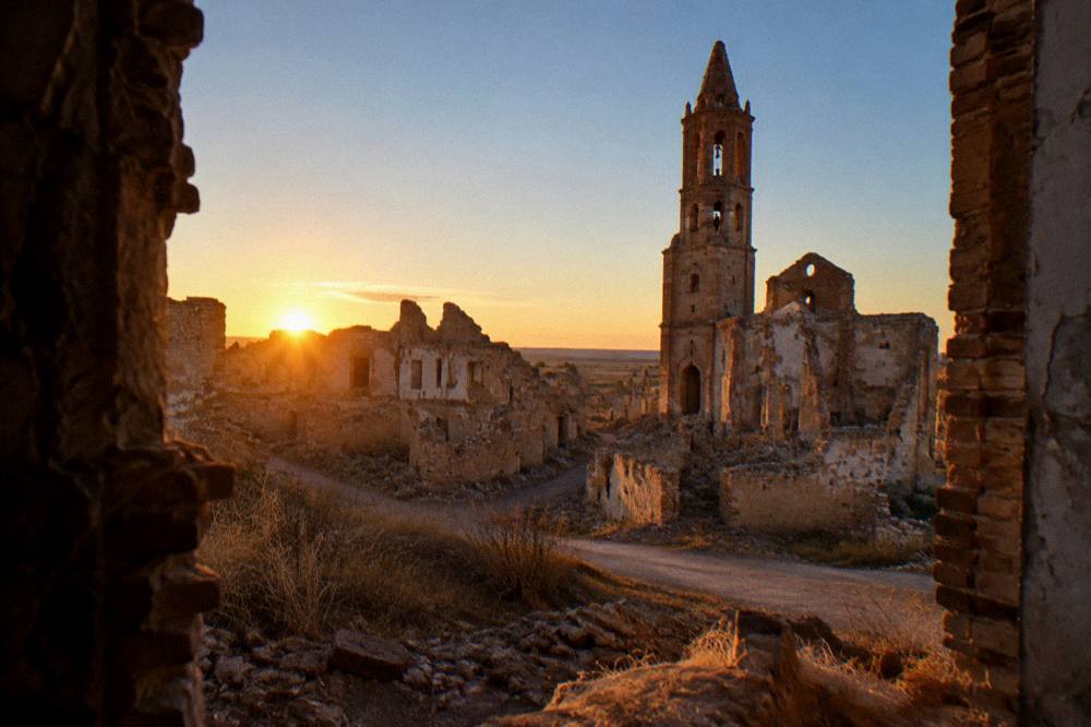 Sun low over the collapsed rooftops and empty lanes of Belchite old town