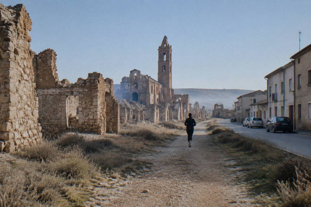 A quiet street in new Belchite with plain post-war houses and parked cars