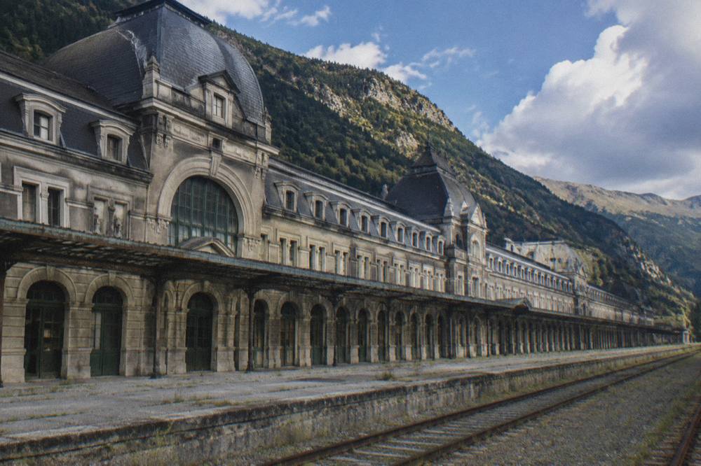 Rows of empty stone arches along the facade of a large abandoned station building