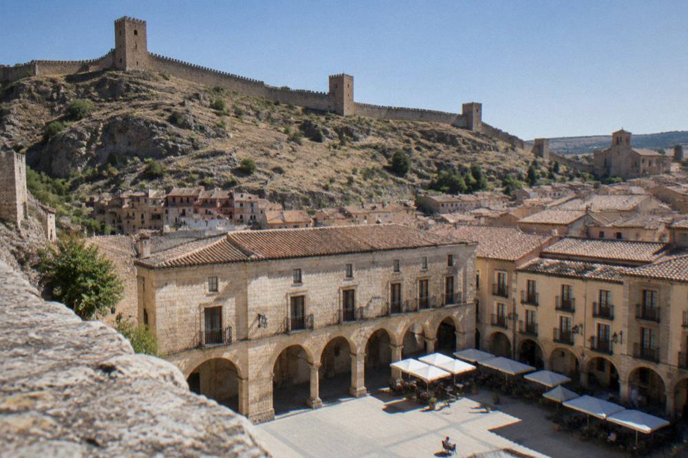 An arcaded main square in a small Spanish town with café tables under stone arches