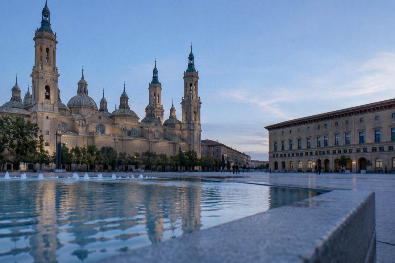 A quiet stone street in Huesca's old town with mountains rising behind the rooftops