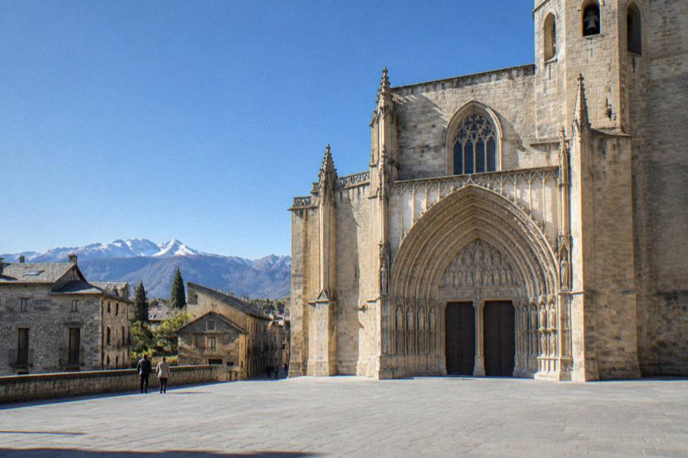 A stone mountain village with slate roofs under high peaks in the Aragonese Pyrenees