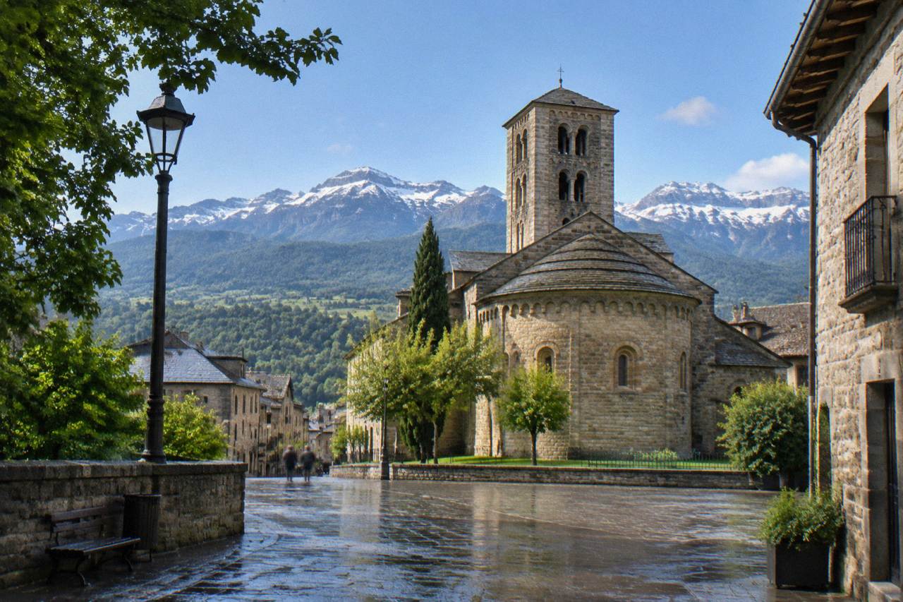 Mountain peaks of the Aragonese Pyrenees rising above a small stone town in a green valley