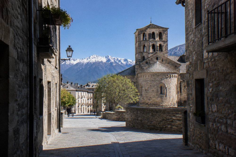 Narrow stone street with old buildings and mountains at the end of the road in a Pyrenean town