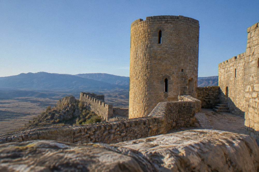 A round stone tower of a castle seen from inside the walls against a blue sky