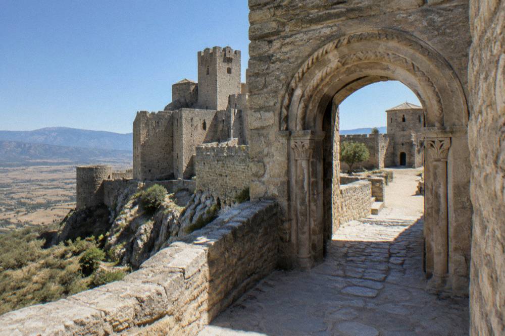 A stone doorway with a carved archway leading into a castle courtyard