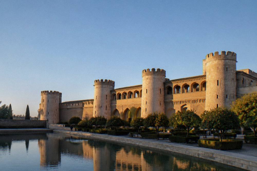 The fortified walls and towers of the Aljafería Palace in Zaragoza in late afternoon light