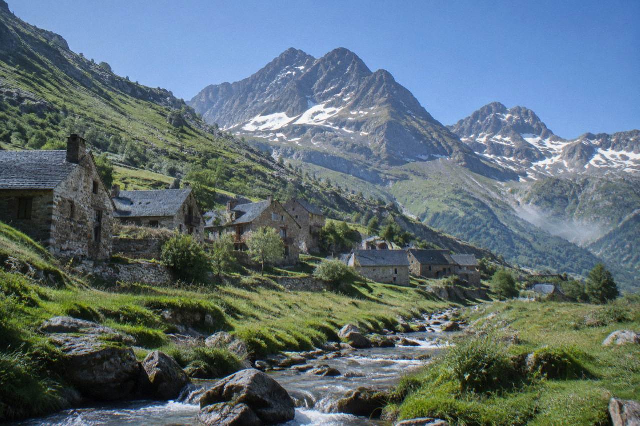 Mountain village with stone houses beneath high peaks on a clear day in the Aragonese Pyrenees