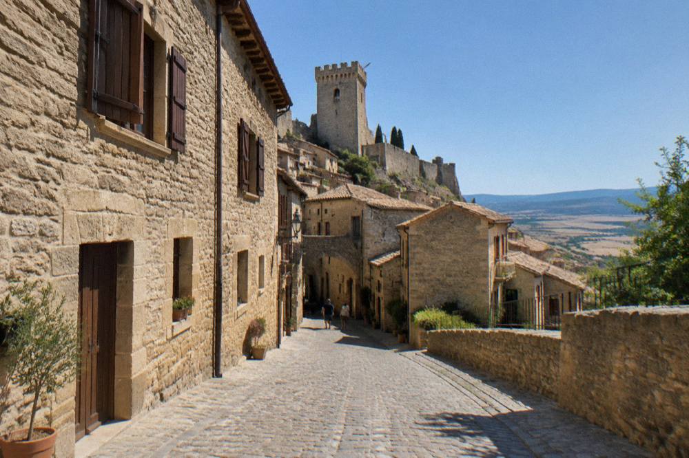 A cobbled street of stone houses with wooden shutters in a medieval Aragonese town
