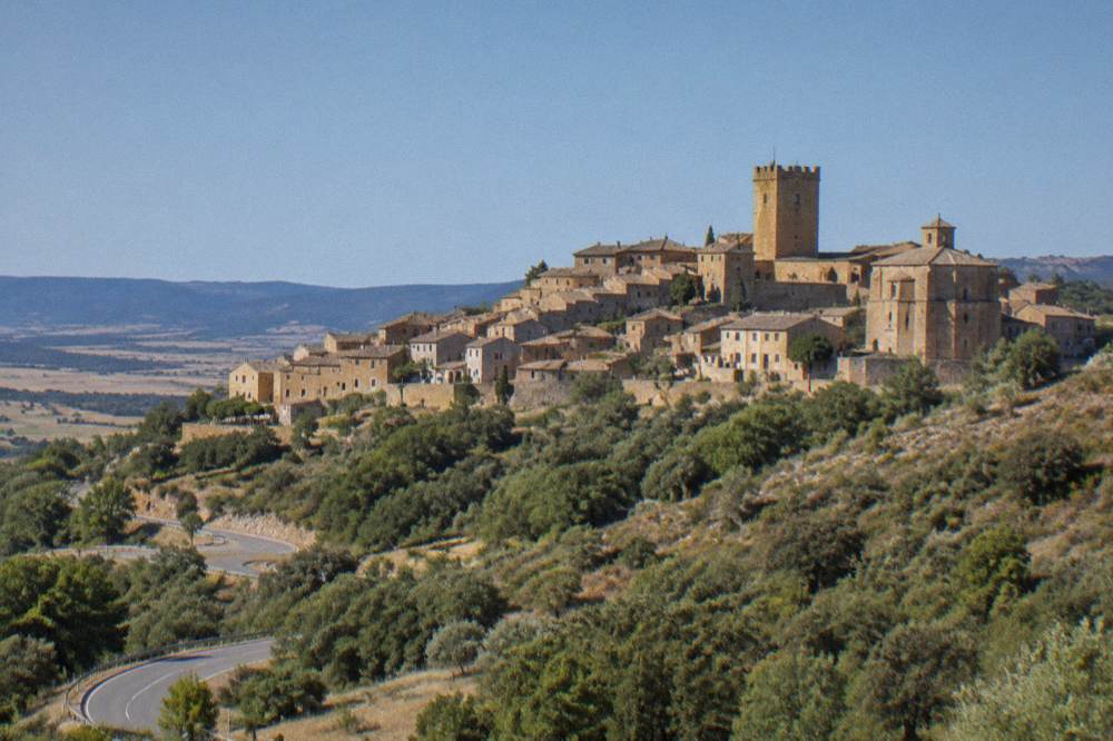 A country road winding through wooded hills towards a hill town in northern Aragon