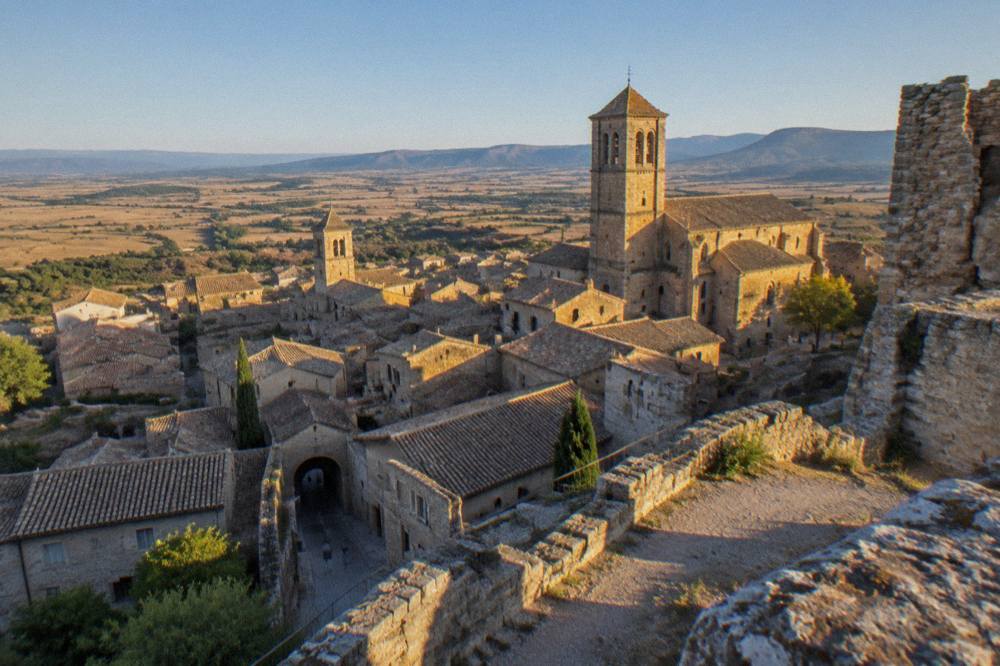 The rooftops and church towers of a hill town seen from a castle ruin at golden hour