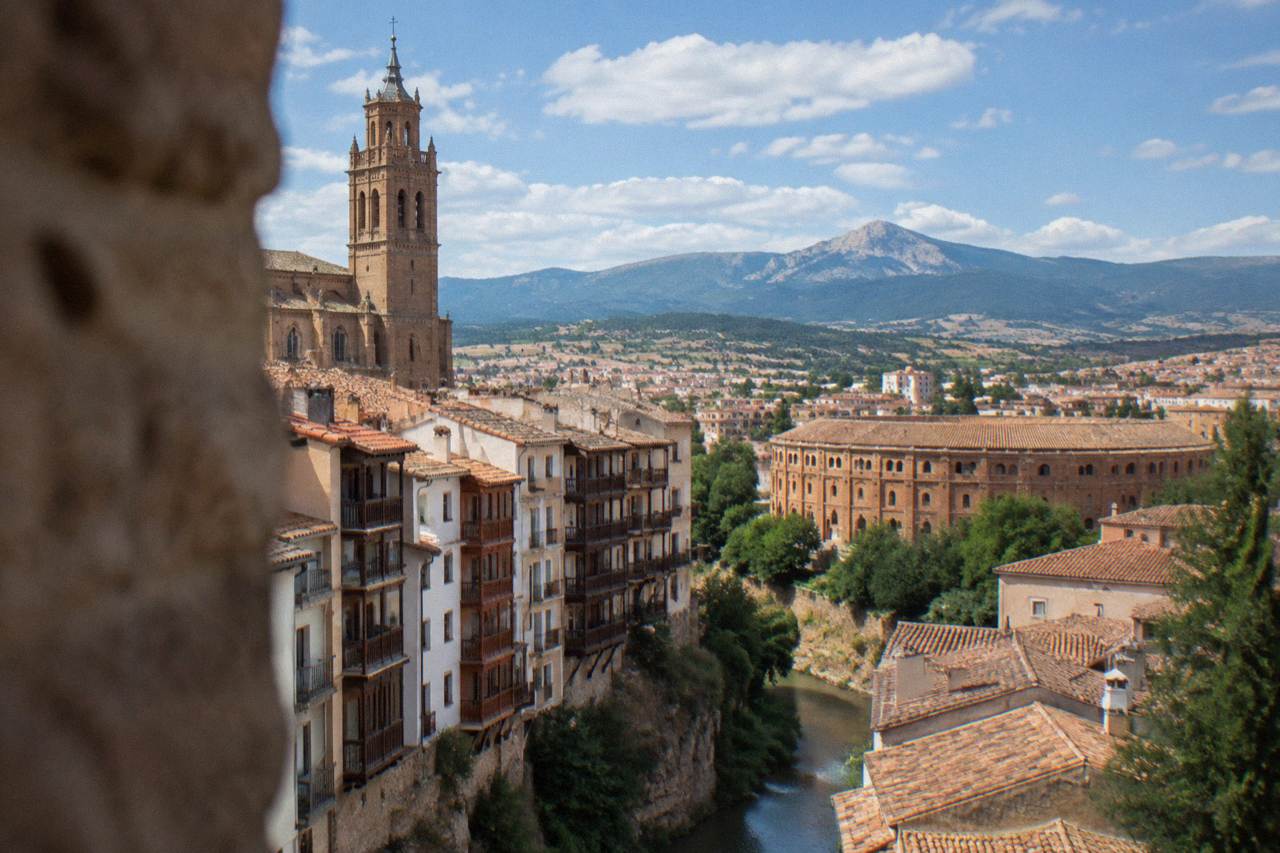 A view over red brick rooftops of Tarazona toward the green slopes of the Moncayo mountains
