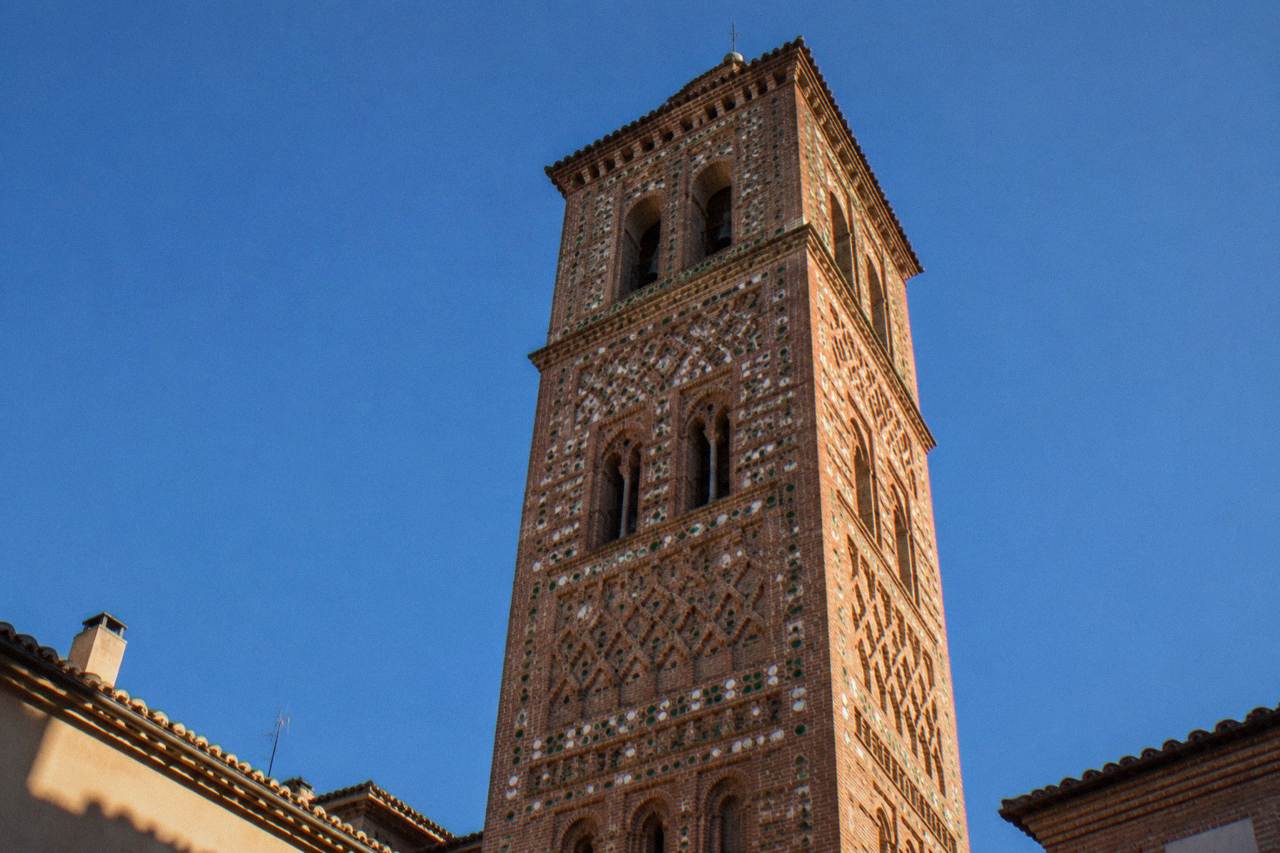 Terracotta brick towers rising over the rooftops of a small Spanish city under a clear sky