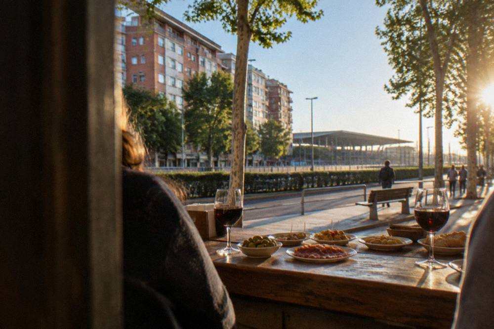 A rustic bar counter laid with small plates of tapas and glasses of red wine