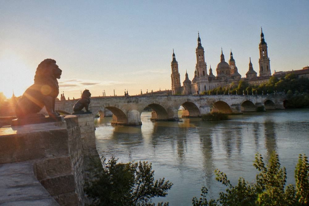 The Ebro river at sunset with the Puente de Piedra bridge and the basilica behind it