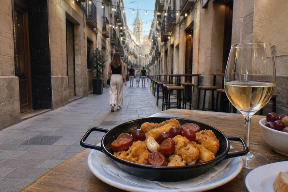 A pan of golden fried breadcrumbs with grapes, chorizo and garlic being served at a table