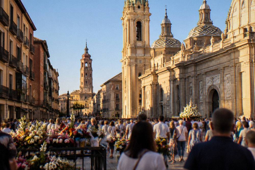 Flower offerings and crowds filling a wide plaza in front of the basilica during a festival day