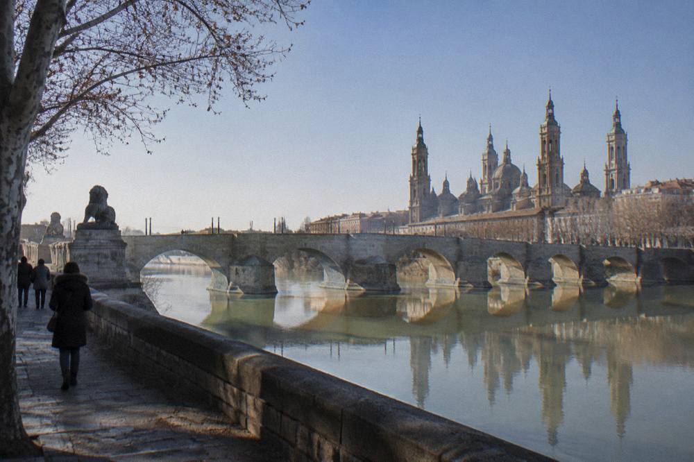 The Puente de Piedra and the Ebro river in winter, with the stone bridge reflected in calm water