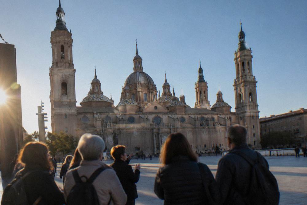 A guided walking group gathered in Plaza del Pilar with the basilica towers behind them