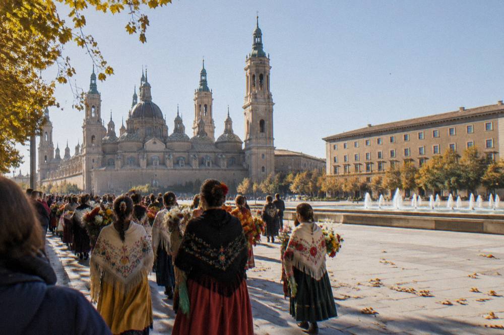 Crowds in traditional dress filling a city street during the Ofrenda de Flores flower parade in Zaragoza