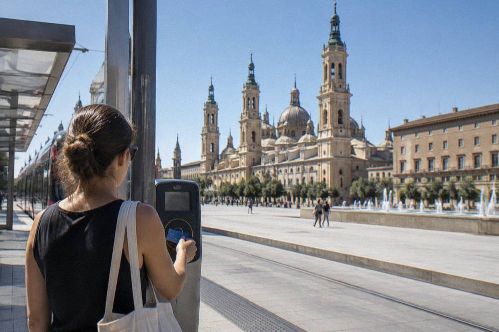 A passenger tapping a transport card at a tram platform validator in Zaragoza