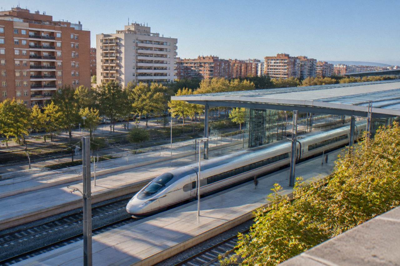 High speed train standing at a modern railway station platform under a glass roof