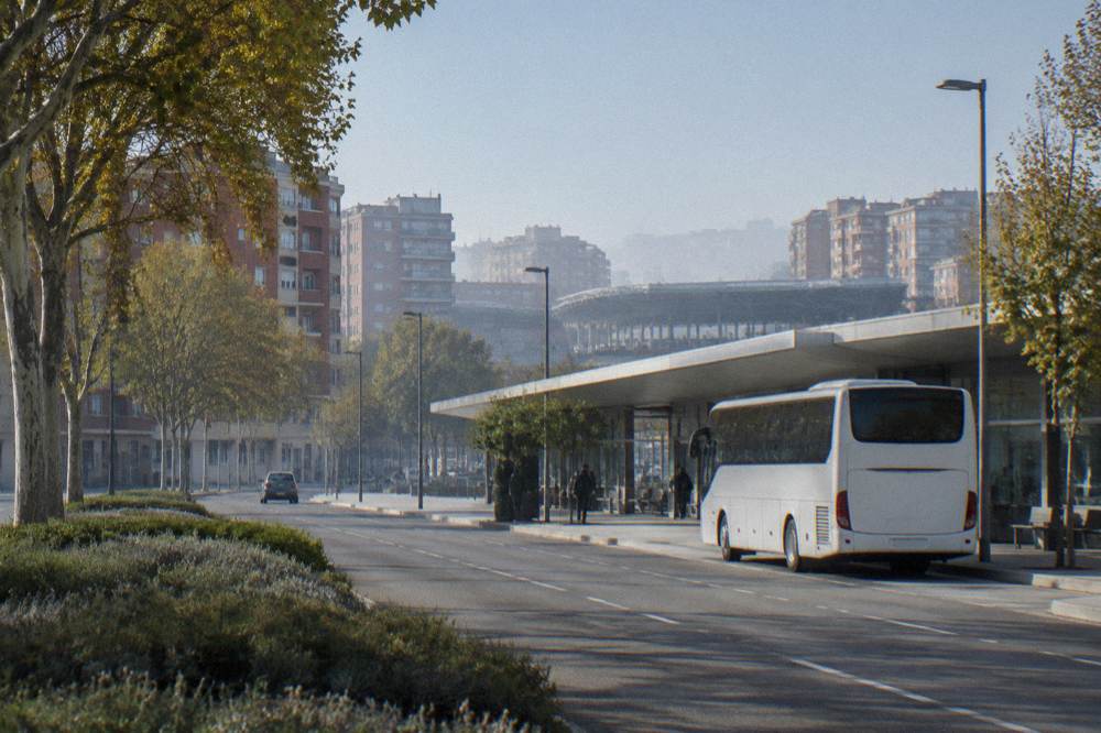 A white airport shuttle bus parked at a kerb outside a small terminal building