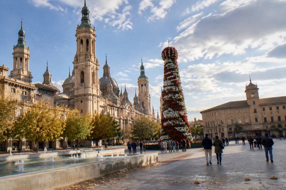A tall structure in front of a baroque basilica being covered with thousands of red and white flowers