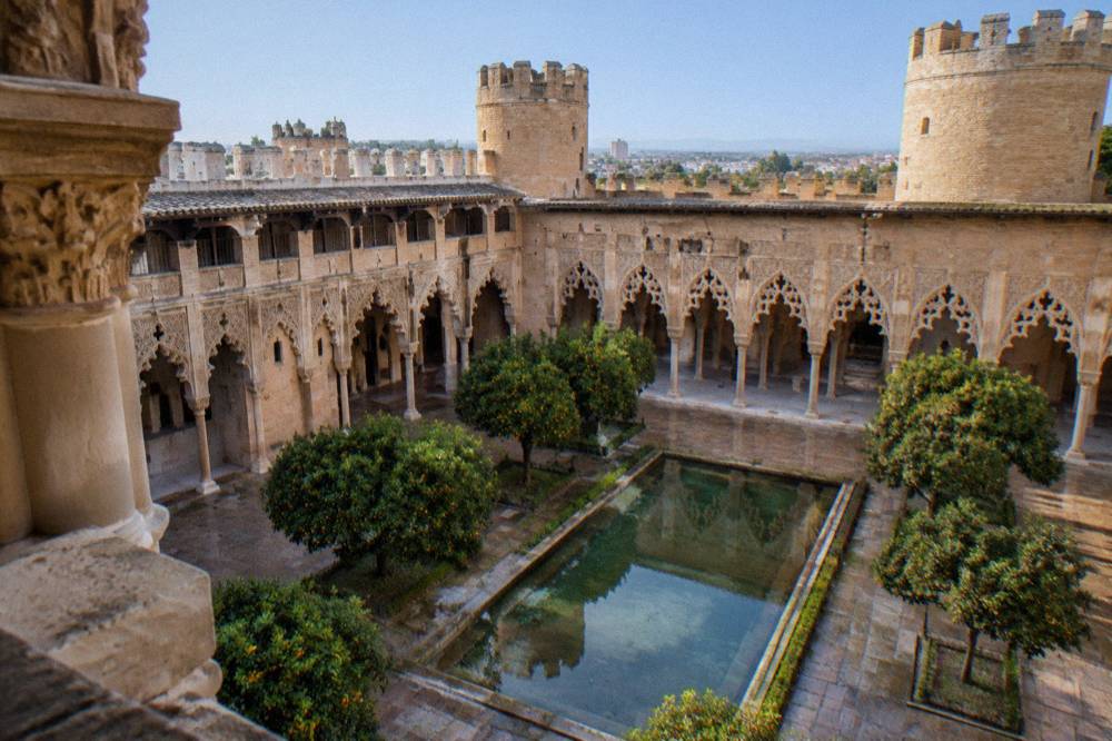 The arched courtyard of the Aljafería palace in Zaragoza with intricate Islamic stonework