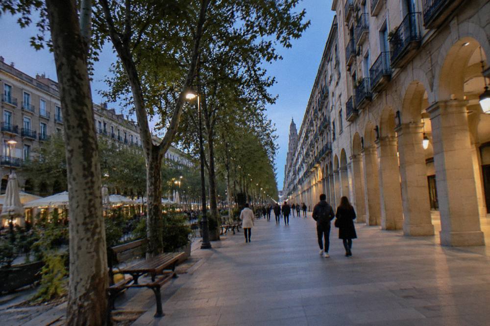 A sunny pedestrian street with arcaded buildings near Paseo de la Independencia in central Zaragoza