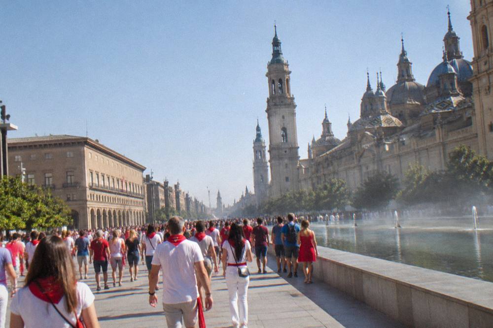 Crowds in bright clothing filling a central street during a festival in Zaragoza
