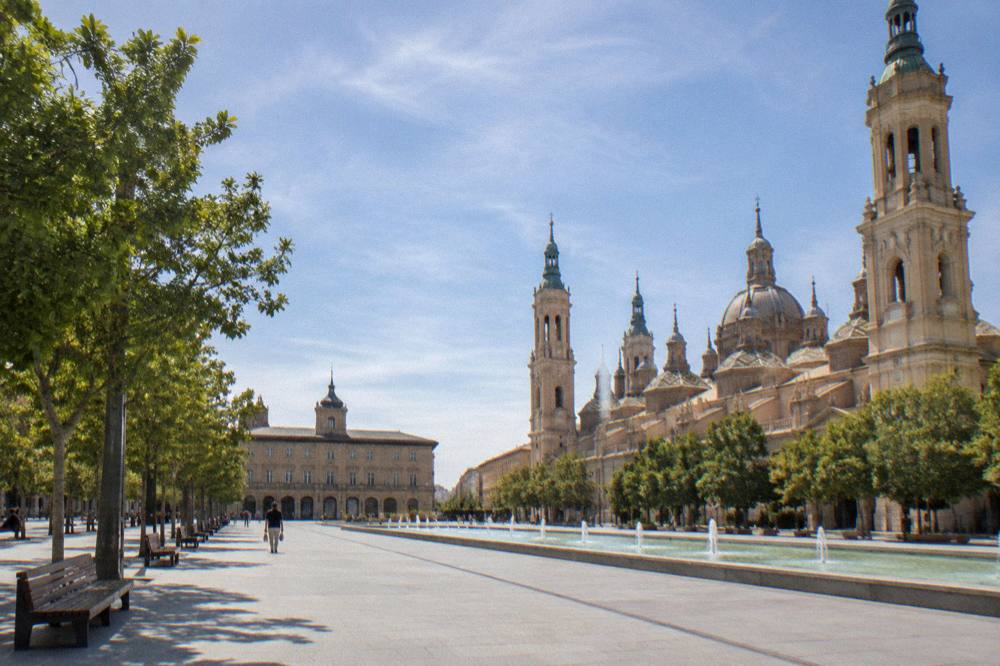 Tree-lined pedestrian promenade in central Zaragoza with benches along the walkway