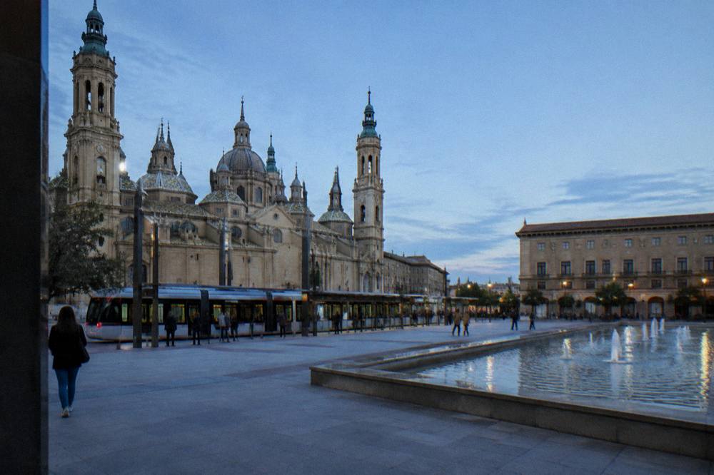 Tram stopped at a central Zaragoza stop with level boarding platform and passengers waiting