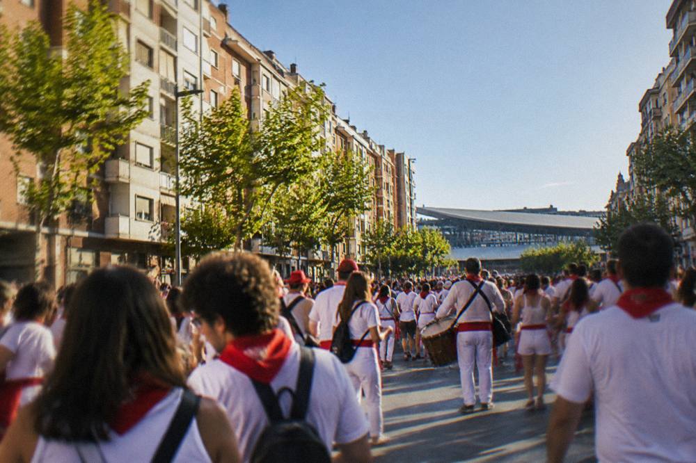 Crowds in festive clothing filling a city street lined with historic buildings during a festival
