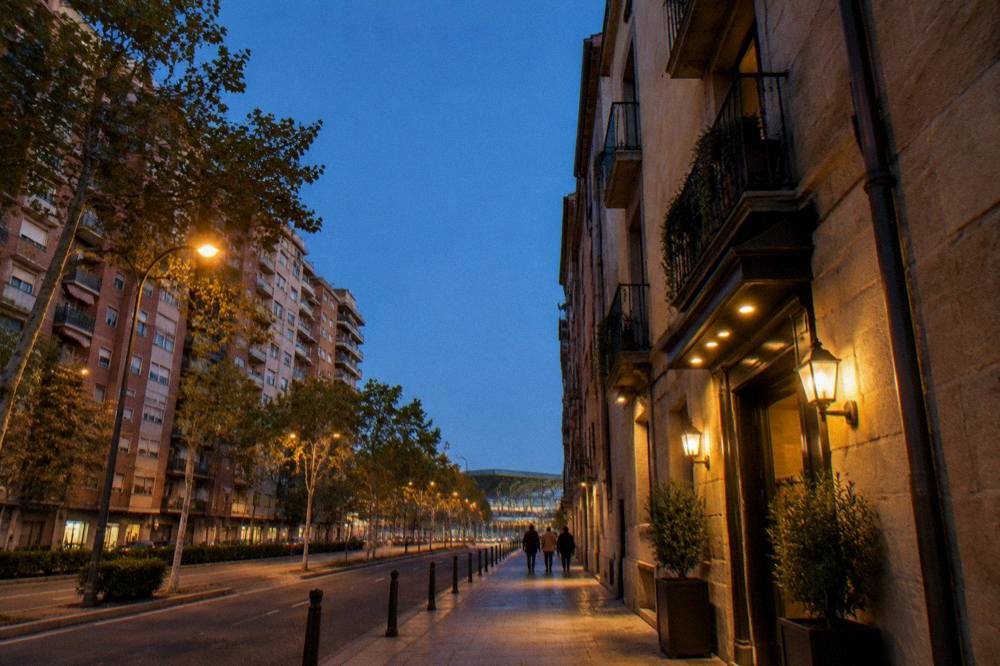 A narrow historic street with stone buildings and a small hotel entrance with warm evening lighting