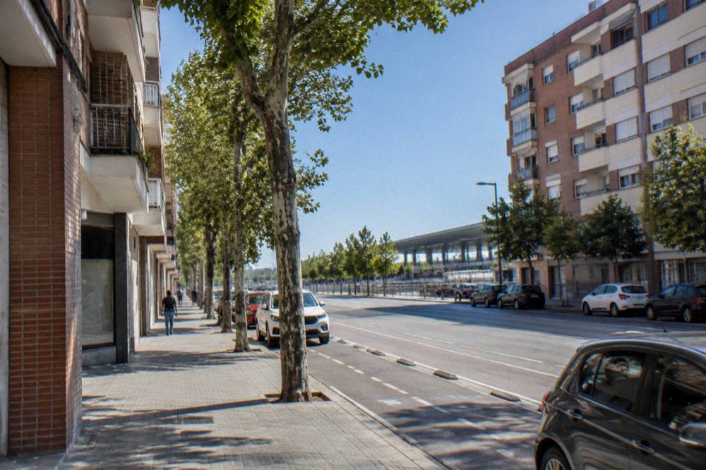 A quiet residential street with apartment buildings and small shops in a Spanish city district