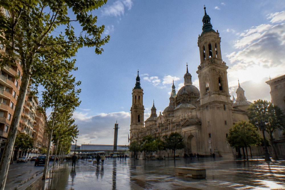 A large baroque basilica with domed towers beside a wide European square