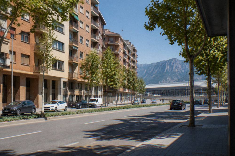 A mountain railway station with a large stone building surrounded by high peaks