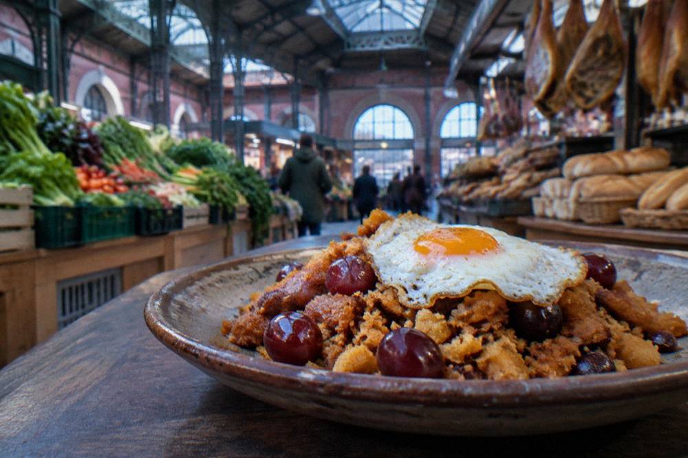 Fried migas breadcrumbs with grapes and a fried egg on a rustic plate