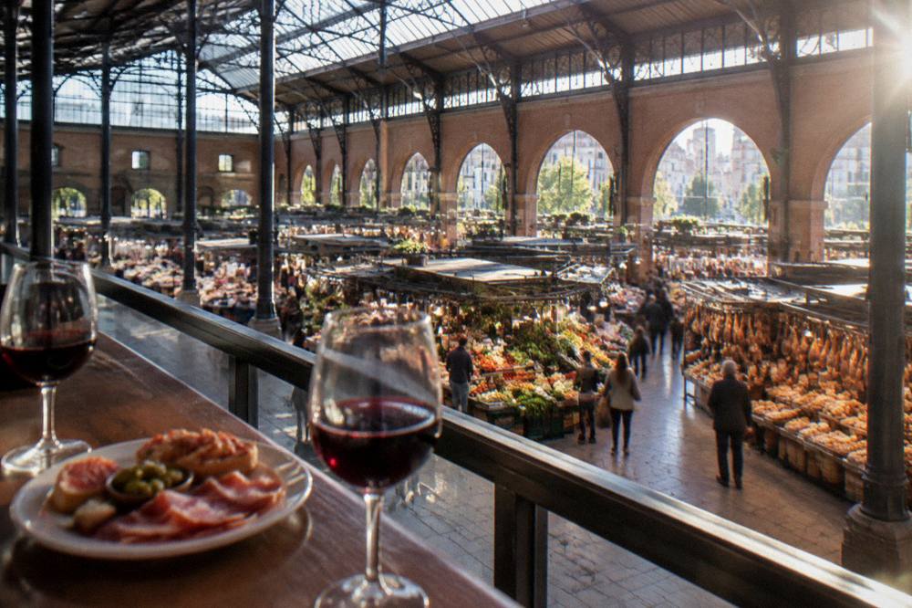 Glasses of red wine and a plate of tapas on a bar top