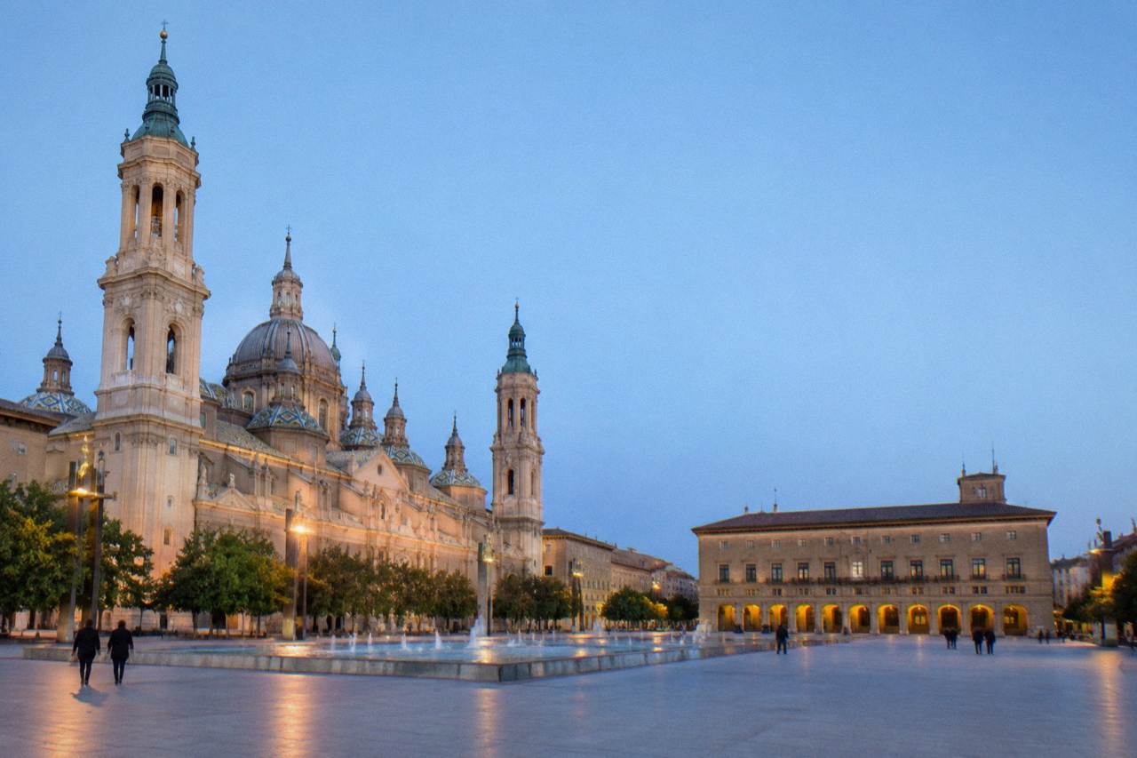 A quiet stone arcade in Zaragoza's old town with warm evening light on the arches