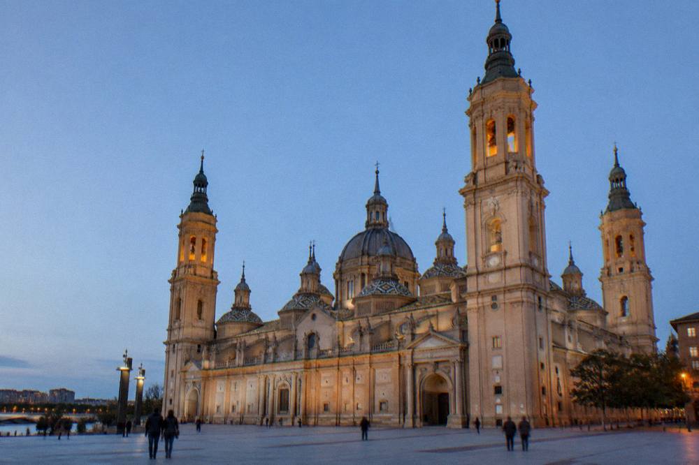 The Basilica del Pilar and its towers seen across a plaza at dusk