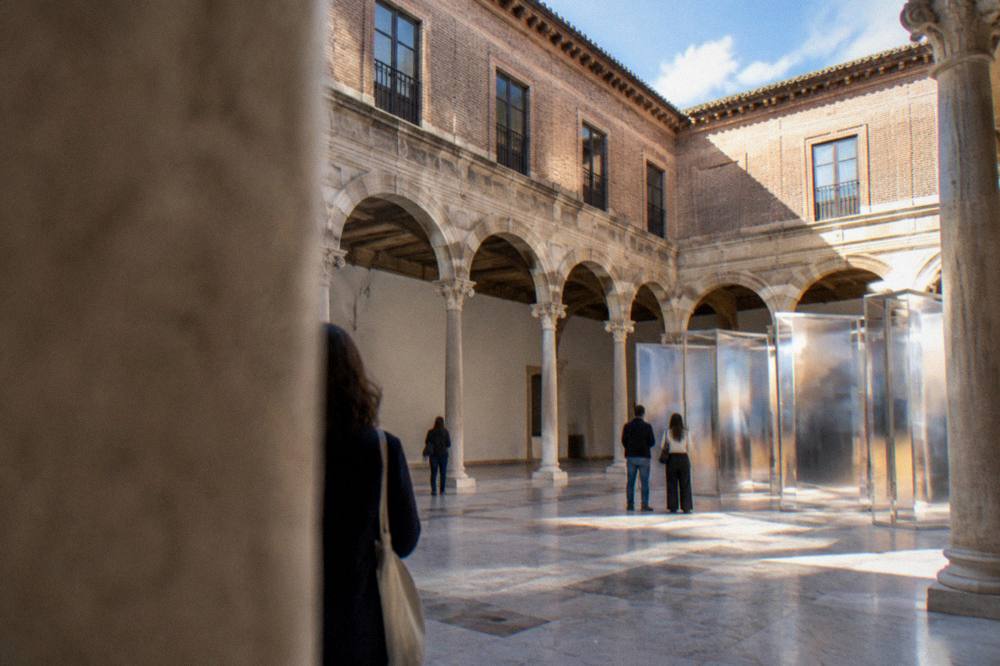 A bright contemporary art atrium with visitors looking at a large installation