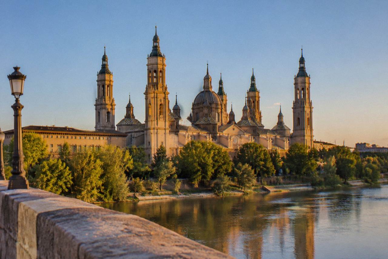 The Basílica del Pilar and its towers seen from the Puente de Piedra across the Ebro at golden hour