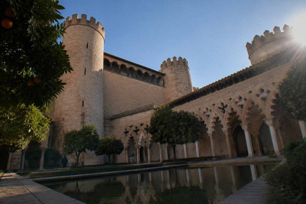 The interlacing horseshoe arches of the Aljafería courtyard lit by soft daylight